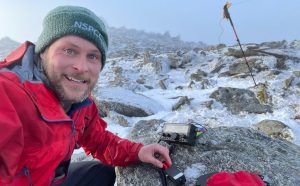 Radio amateur using portable radio on top on a snowy mountain