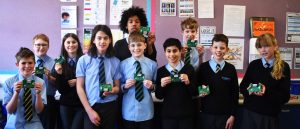 Group of school children each holding up a radio kit they have constructed