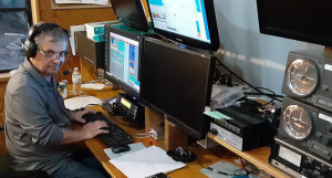 Radio amateur sitting in his shack in front of two screens