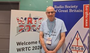 A man standing between a WRTC and an RSGB banner